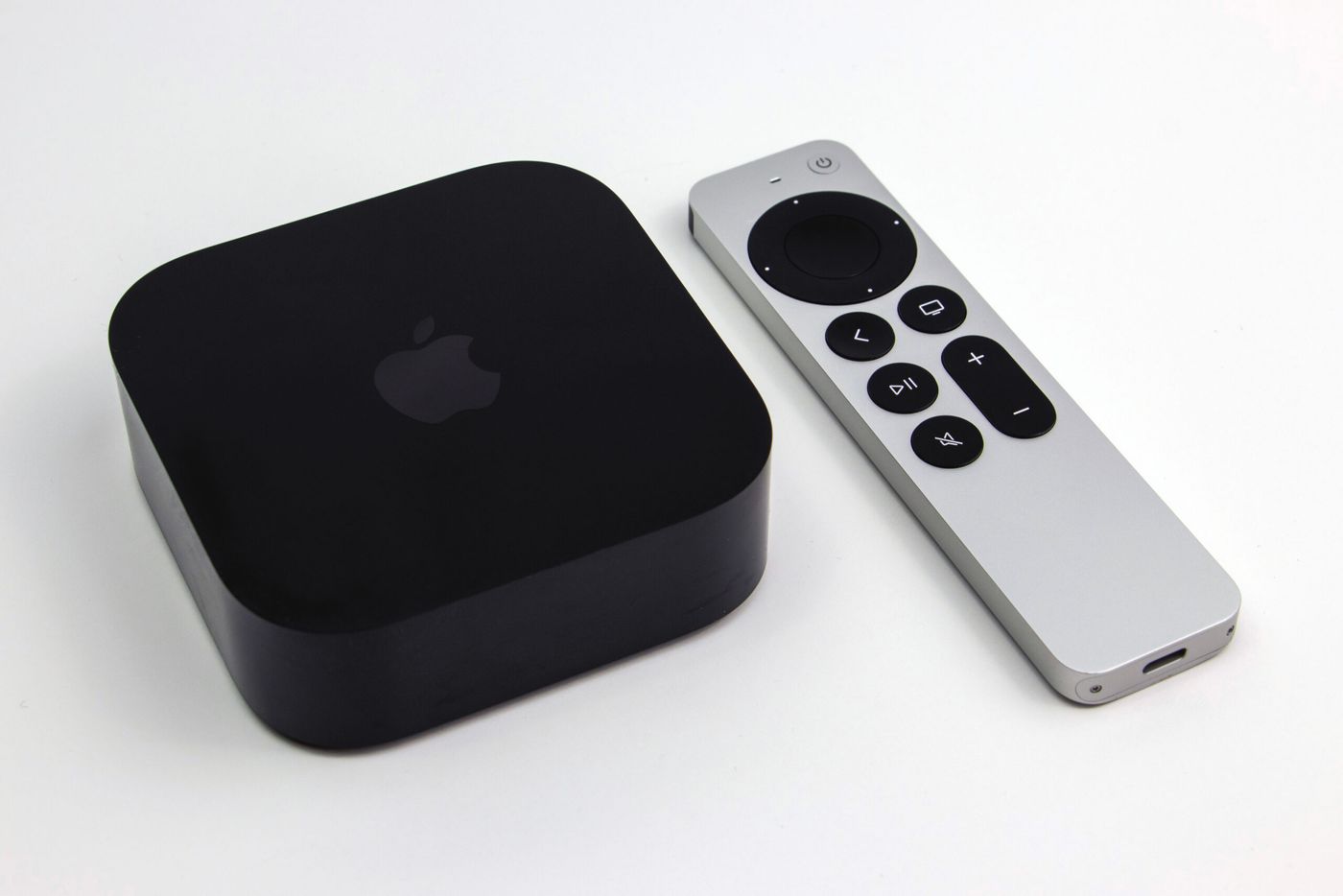 Apple TV 4K third-generation box beside its Siri Remote on a wooden surface