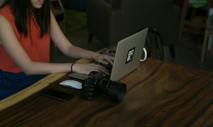 Content creator reviewing a laptop beside camera equipment at a desk