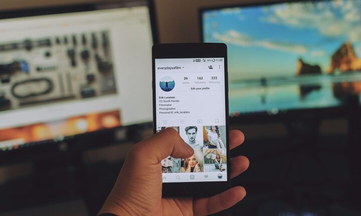 Person holding a smartphone displaying an Instagram profile