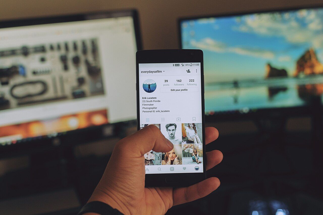 Person holding a smartphone displaying an Instagram profile