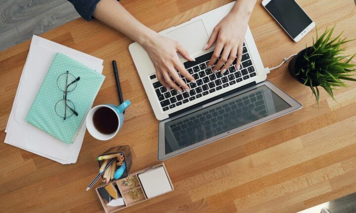 Hands typing on a laptop at an office desk, illustrating newsletter publishing work