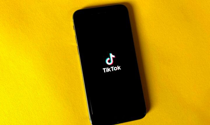 TikTok logo displayed on a smartphone against a yellow background