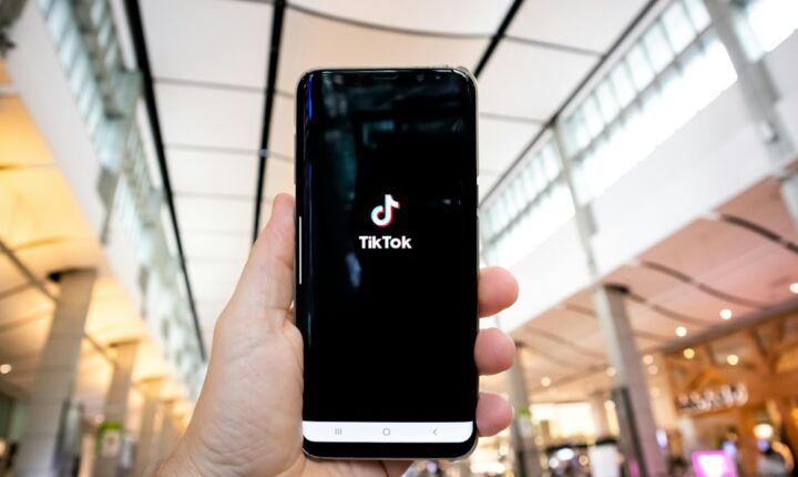 Person holding a smartphone with the TikTok app open inside a shopping mall