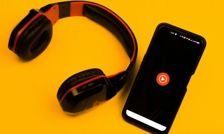 YouTube Music app displayed on a smartphone beside headphones