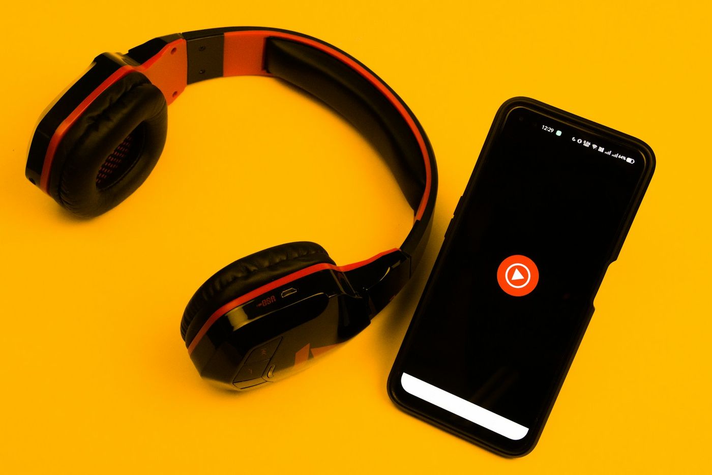 YouTube Music app displayed on a smartphone beside headphones